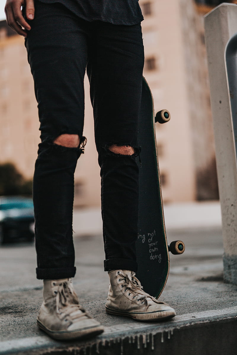 person wearing black denim pants while holding skateboard, HD phone wallpaper