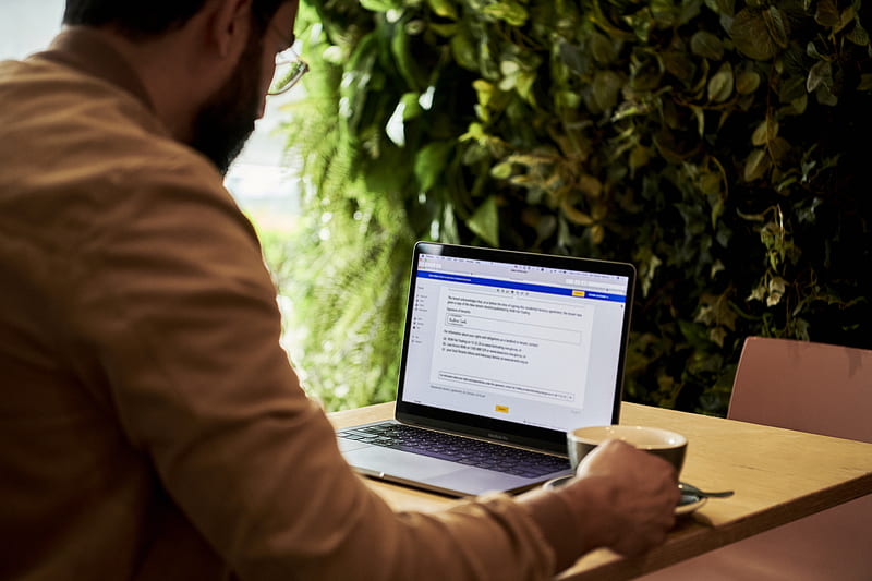 man in brown jacket looking at contract on DocuSign on a laptop, HD wallpaper