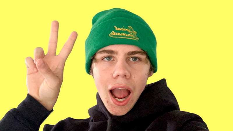 The Kid Laroi Is Wearing Black T-Shirt And Green Woolen Cap On Head Showing Victory Sign In Yellow Background The Kid Laroi, HD wallpaper