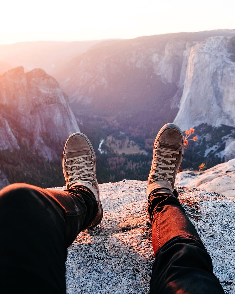 person wearing brown lace-up sneakers sitting on rocky mountain during daytime, HD phone wallpaper