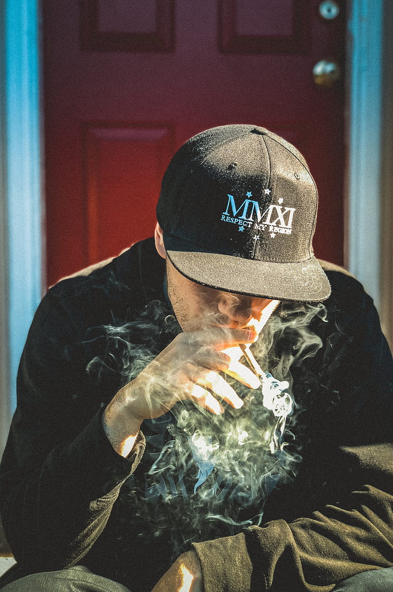 man in black cap and shirt sitting near door while smoking, HD phone wallpaper