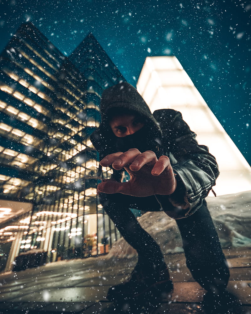 close-up graphy of man kneeling on ground front of gray high-rise building during snow weather, HD phone wallpaper
