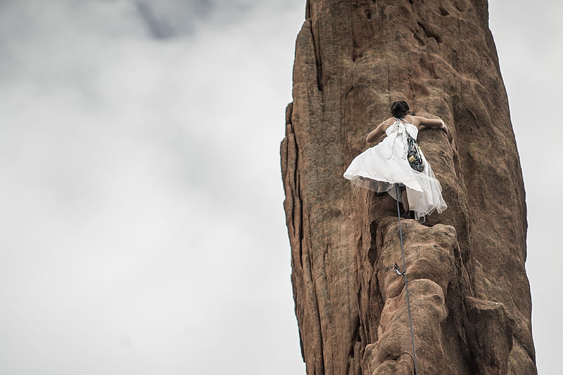 woman wearing white wedding dress climbing on brown rock under white sky, HD wallpaper