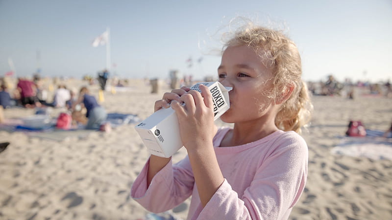A girl drinking a carton of Boxed Water on the beach, HD wallpaper