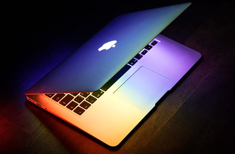 A MacBook lit up in rainbow colors on a wooden surface, HD wallpaper