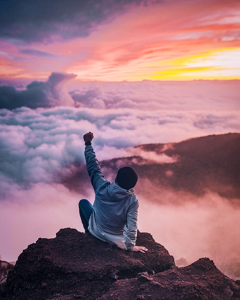 man sitting on mountain cliff facing white clouds rising one hand at golden hour, HD phone wallpaper