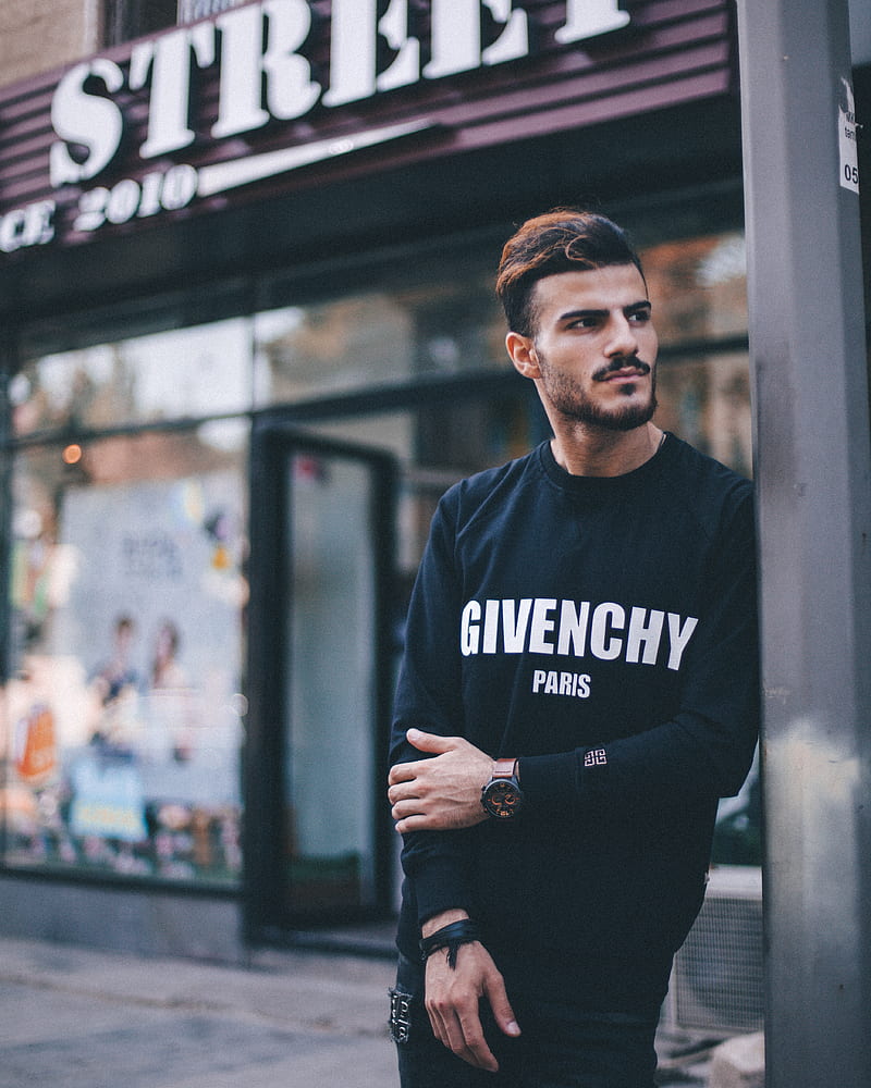 man in black Givenchy sweatshirt standing beside of post in front of Strek store during daytime shallow focus graphy, HD phone wallpaper