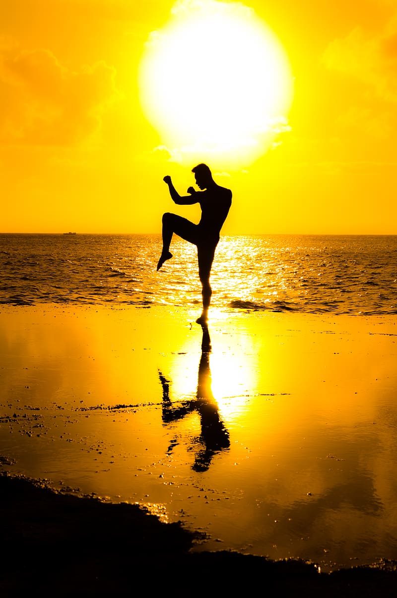 Side view silhouette of slim female standing in Mountain pose with arms up  while practicing yoga on floating paddle board against sunset sky stock  photo