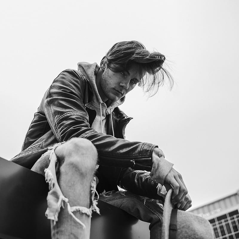 grayscale of man swearing leather jacket sitting on floor near building, HD phone wallpaper