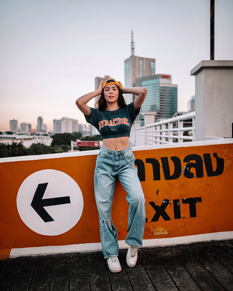 woman in black tank top and blue denim jeans standing on yellow and black road sign, HD phone wallpaper