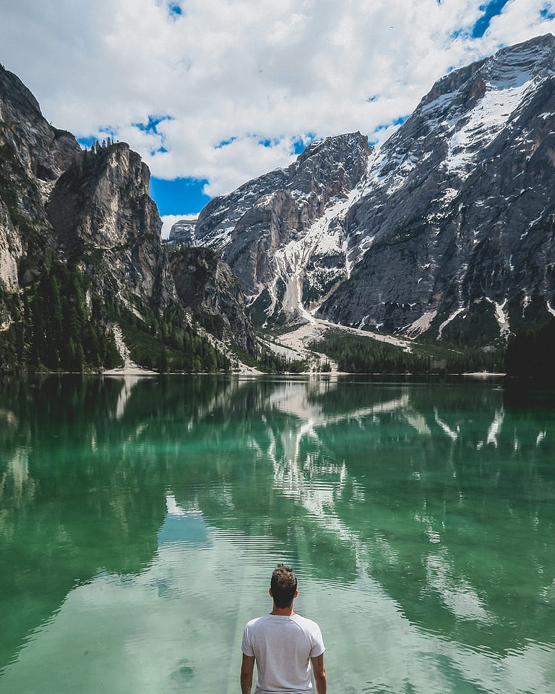 man standing in front of lake and cliff under white clouds and blue sky, HD phone wallpaper
