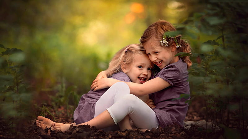 Smiley Cute Sisters Are Hugging Each Other Sitting On Dry Leaves In Blur Green Background Cute, HD wallpaper