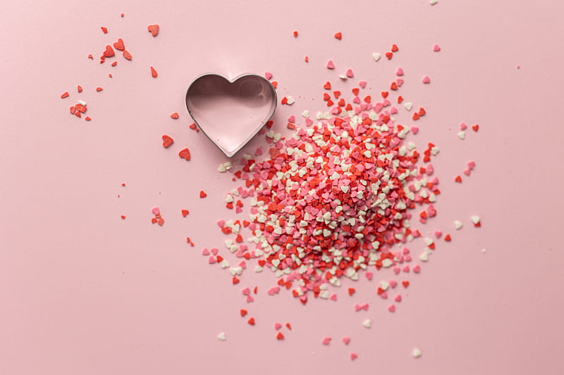 Top view of form for cooking in shape of heart near small handful of confetti on pink background, HD wallpaper