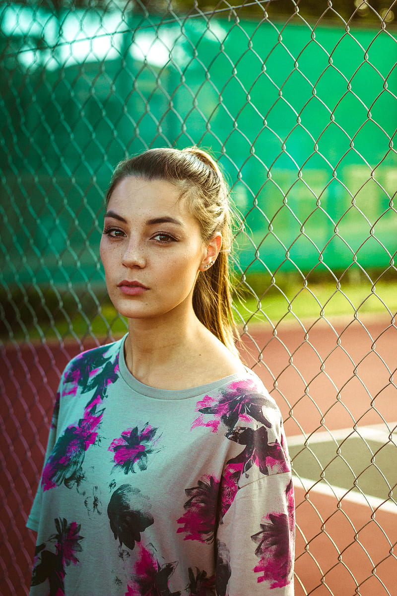 woman wearing floral top beside chain link fence during day, HD phone wallpaper