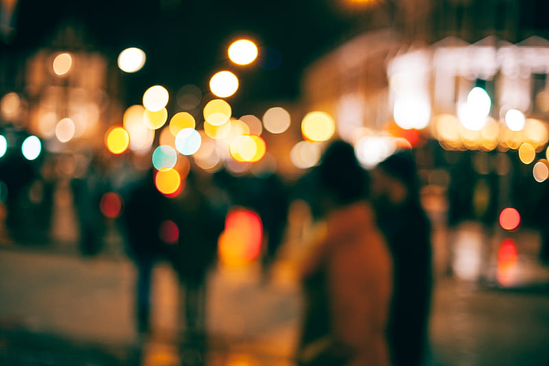 An out-of-focus look at people walking outside in a town at night with with blurs of dotted light all around, HD wallpaper