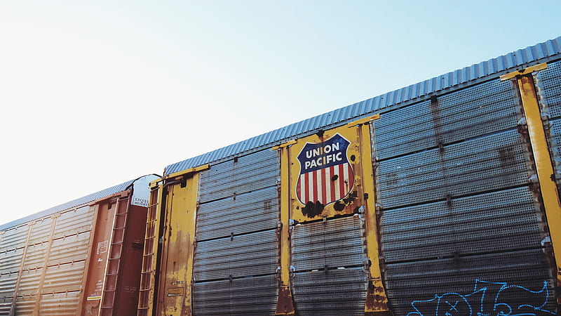 / an old rusting union pacific railcar with blue graffiti on it passing a grassy area under a clear sky, union pacific freight car, HD wallpaper