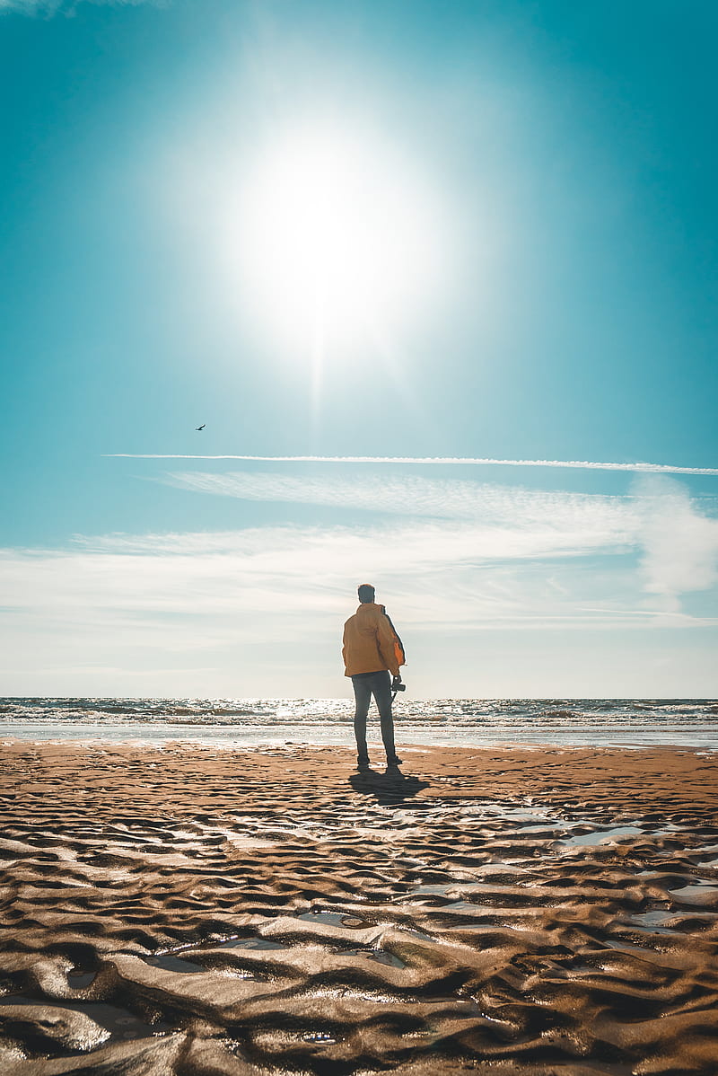 man in yellow jacket standing in front of shore, HD phone wallpaper