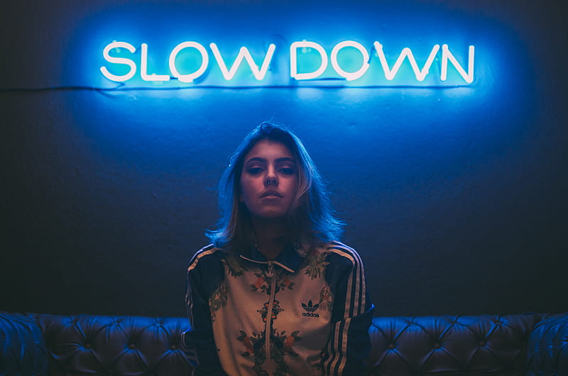 woman sitting on brown sofa under slow down neon signage, HD wallpaper