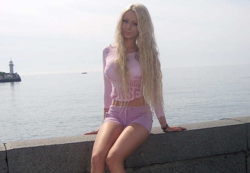 Valeria Lukyanova, barbie doll look a like, stone wall, headland, cream top, seaside, platinum blonde, sitting, violet coloured pants, lighthouse, HD wallpaper