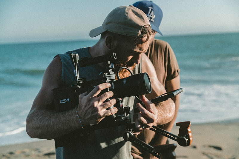 man holding video camera standing near body of water, HD wallpaper