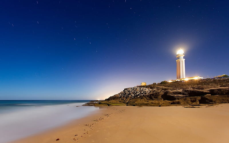 stars over lit lighouse, beach, stars, light, lighthouse, HD wallpaper