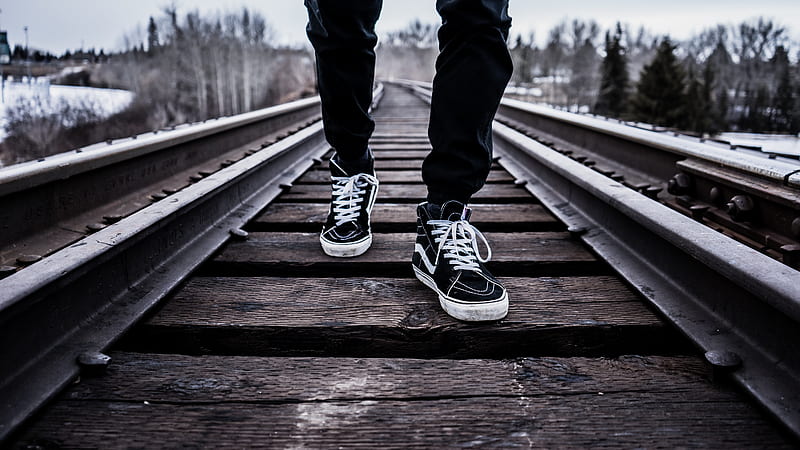 person wearing pair of black-and-white Vans Old Skool shoes walking on brown train tracks during winter, HD wallpaper