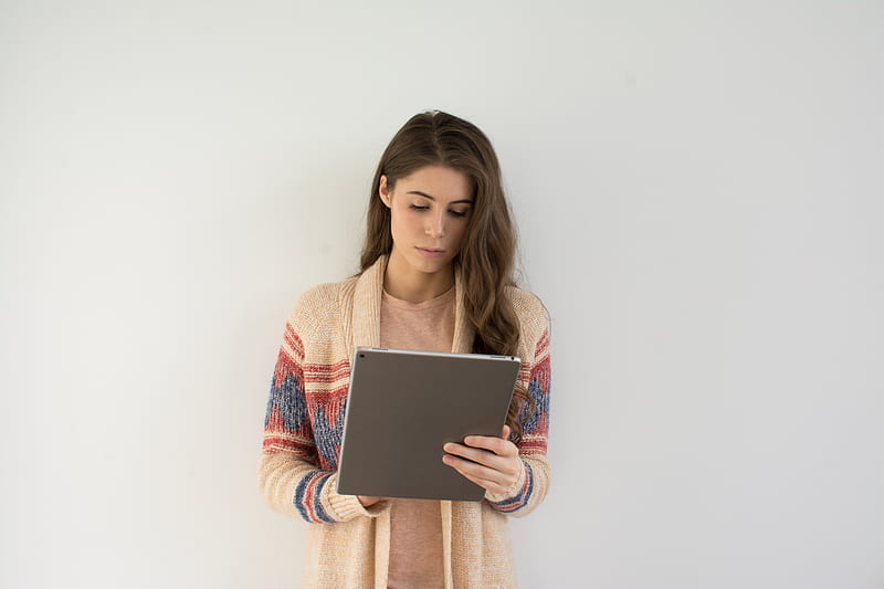 woman in beige, gray, and red sweater holding silver tablet computer, HD wallpaper