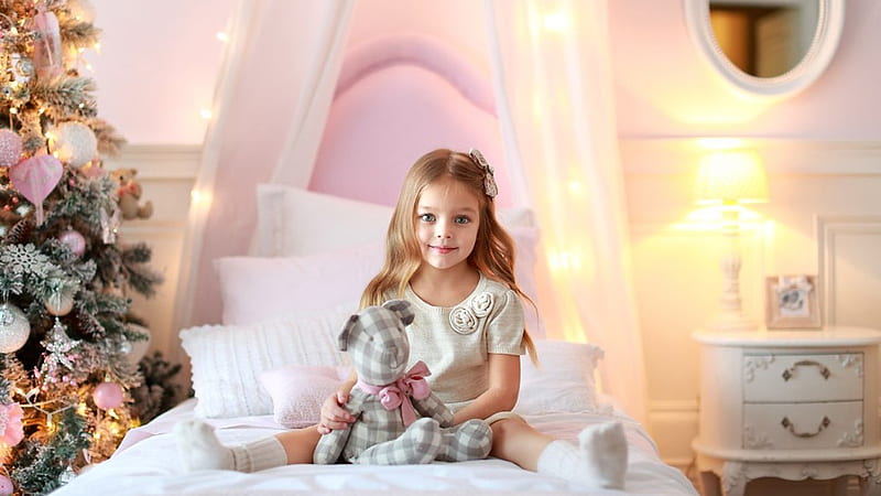 Smiley Cute Little Girl With Doll Is Sitting On White Bed Wearing White ...