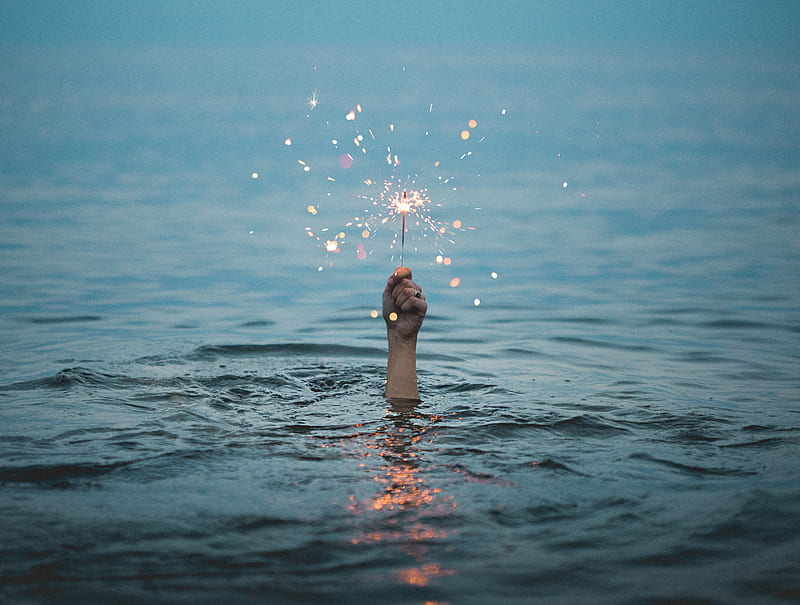 person submerged on body of water holding sparkler, HD wallpaper