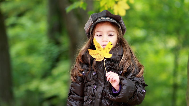 cute girl is having yellow leaf in hand wearing black jacket and cap in green blur background cute, HD wallpaper