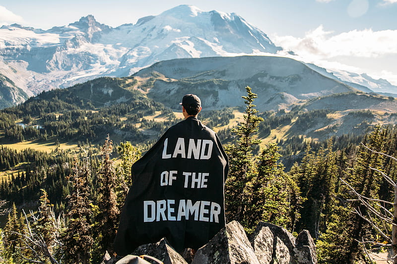 person standing on mountain peak with black land of the dreamer-printed cape on his back, HD wallpaper