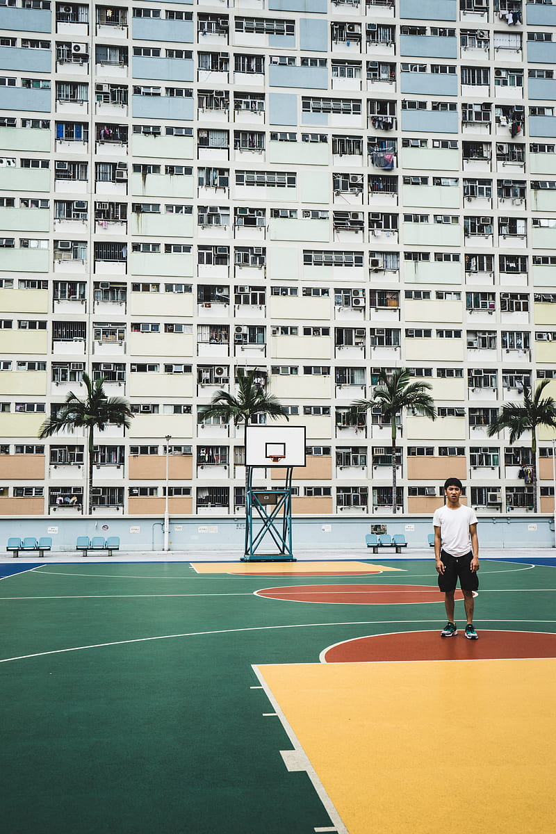 man standing on basketball court near building, HD phone wallpaper