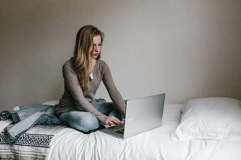 woman typing on MacBook Pro while sitting on bed in room, HD wallpaper
