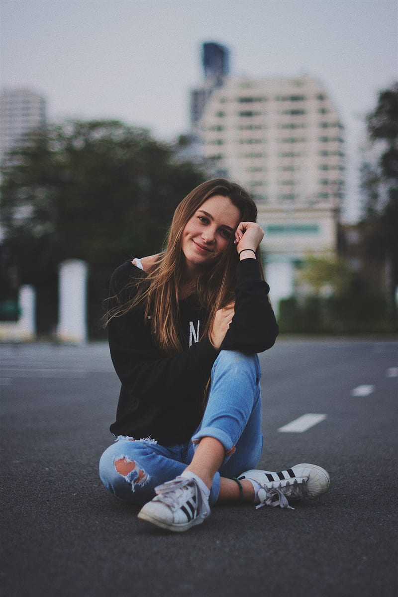 woman smiling while sitting on road with hand resting on top of her knee, HD phone wallpaper
