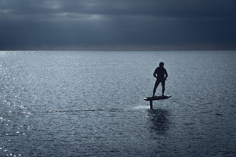 man in black wet suit standing on brown wooden paddle board during daytime, HD wallpaper