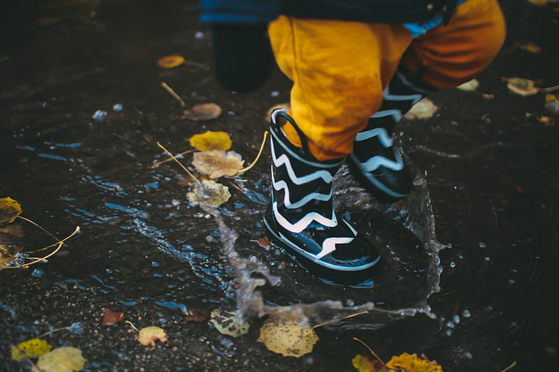 toddler wearing black and white rain boots standing on body of water, HD wallpaper