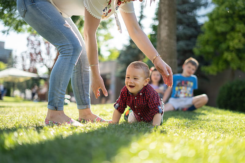 woman in white blouse and blue denim jeans helping a baby crawl on green grass, HD wallpaper