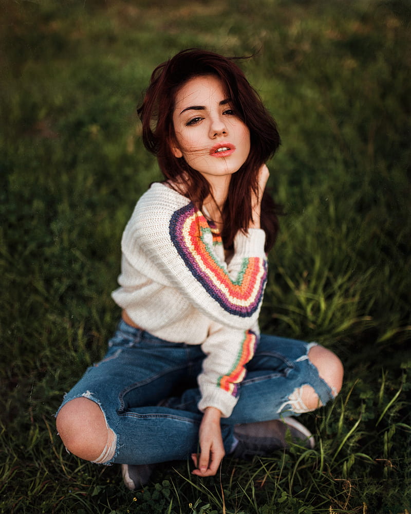 Delaia Gonzalez , women, model, brunette, hair in face, touching hair, looking at viewer, sensual gaze, parted lips, sweater, jeans, torn jeans, sitting, legs crossed, bokeh, depth of field, grass, portrait display, vertical, outdoors, women outdoors, Gustavo Terzaghi, HD phone wallpaper